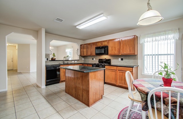 10406 Tenleyton Ln, Houston, TX 77075 - kitchen with black appliances, a center island, light tile patterned floors, and arched walkways