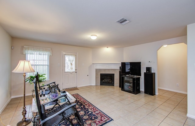 10406 Tenleyton Ln, Houston, TX 77075 - living room featuring arched walkways, light tile patterned floors, a tiled fireplace, and baseboards