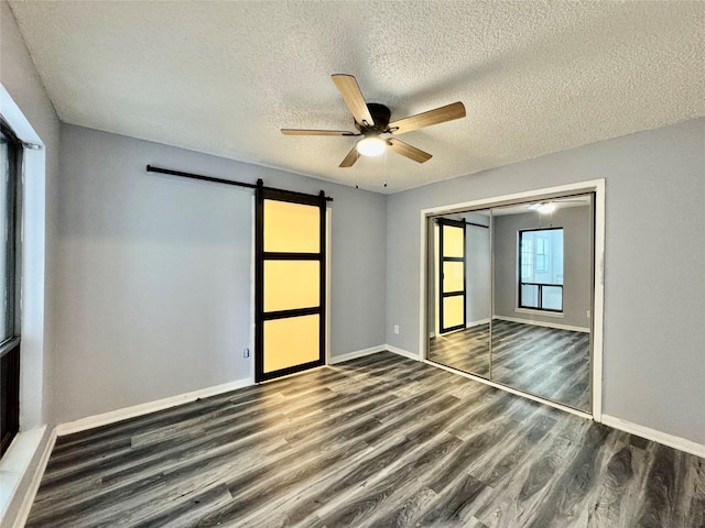 18 Townhouse Ln Unit 18, Trinity, TX 75862 - unfurnished bedroom with a barn door, wood finished floors, a textured ceiling, baseboards, and a closet