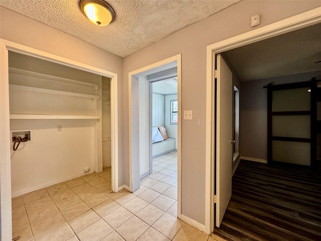 18 Townhouse Ln Unit 18, Trinity, TX 75862 - hall featuring light tile patterned floors, a barn door, a textured ceiling, and baseboards