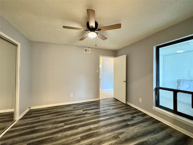 18 Townhouse Ln Unit 18, Trinity, TX 75862 - unfurnished bedroom with dark wood-style flooring, a textured ceiling, baseboards, a ceiling fan, and a closet