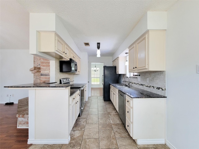 18515 Sweetmeadow Dr, Spring, TX 77379 - kitchen featuring black appliances, cream cabinetry, dark countertops, a sink, and a textured ceiling