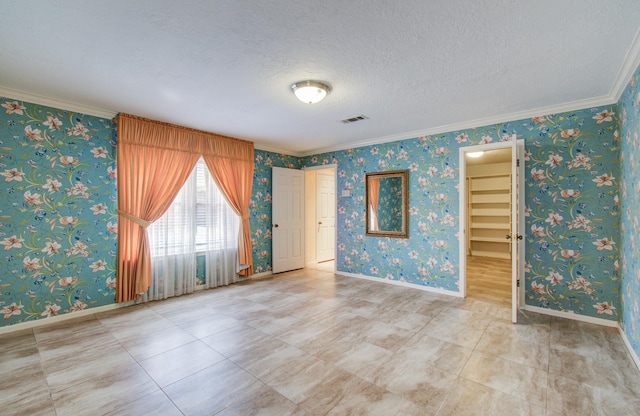 unfurnished room featuring ornamental molding, baseboards, a textured ceiling, and wallpapered walls