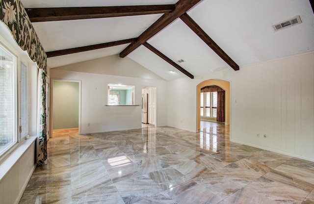 spare room featuring marble tiled floors and arched walkways