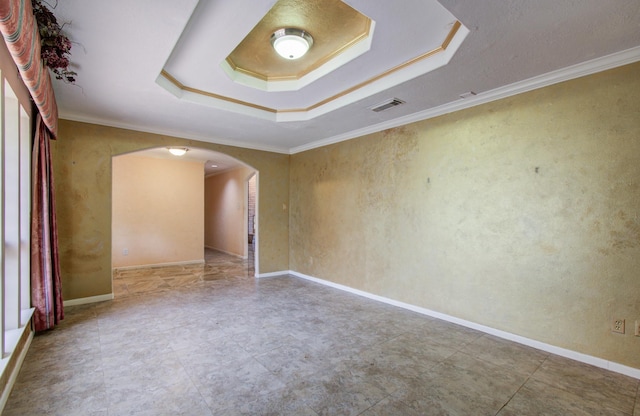 empty room with arched walkways, a raised ceiling, and crown molding