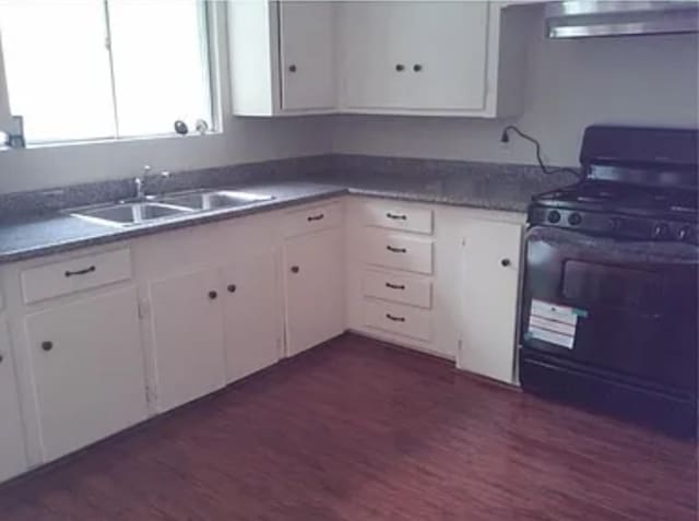 406 Poinsetta St, Lake Jackson, TX 77566 - kitchen with black range with gas cooktop, under cabinet range hood, a sink, dark wood finished floors, and white cabinetry