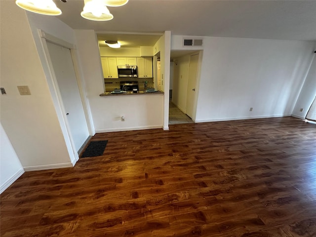 unfurnished living room with dark wood-type flooring and baseboards