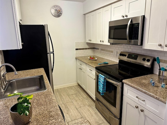 kitchen with stainless steel appliances, a sink, tasteful backsplash, and white cabinets