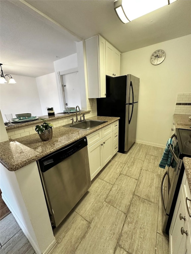 kitchen with stainless steel appliances, a sink, white cabinets, stone countertops, and decorative backsplash
