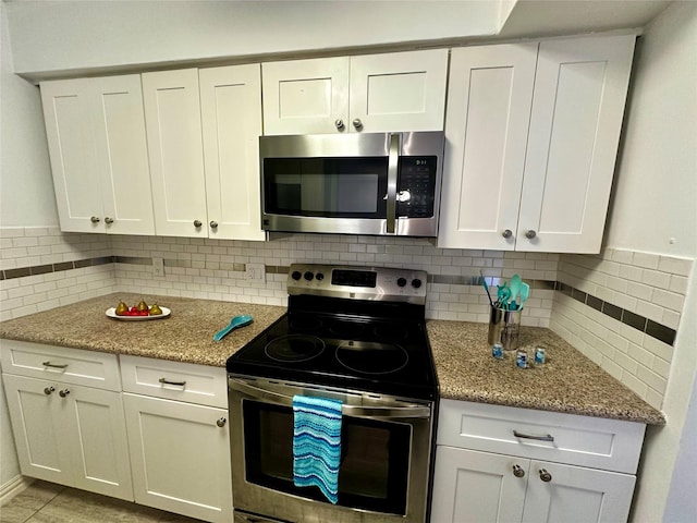 kitchen with stainless steel appliances, white cabinetry, decorative backsplash, and light stone counters