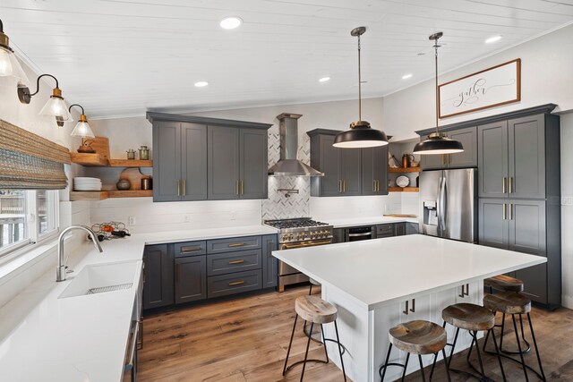 30 N Curlew St, La Marque, TX 77568 - kitchen featuring open shelves, stainless steel appliances, wall chimney range hood, a sink, and a kitchen bar