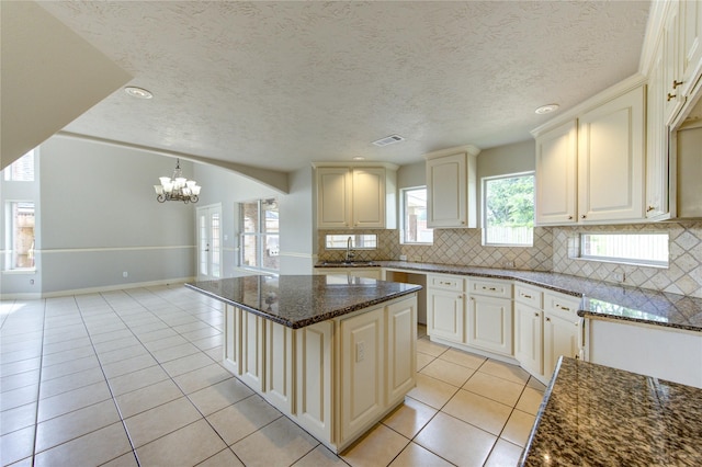 6613 Whitton Dr, Houston, TX 77085 - kitchen with light tile patterned flooring, a chandelier, a sink, dark stone counters, and tasteful backsplash