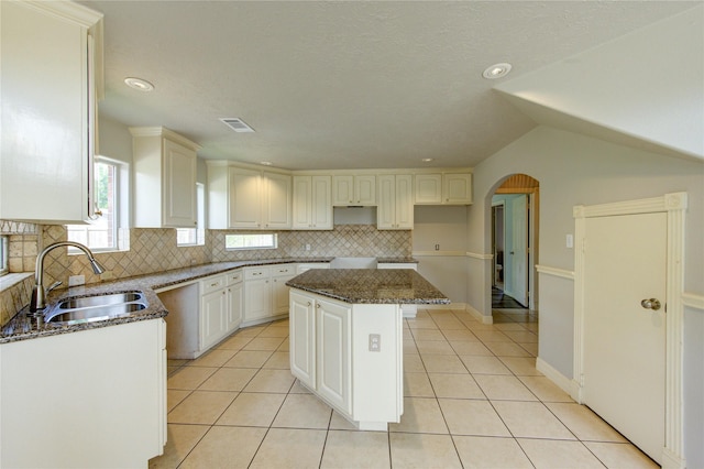 6613 Whitton Dr, Houston, TX 77085 - kitchen featuring a sink, decorative backsplash, light tile patterned floors, a center island, and dark stone counters