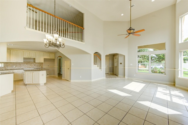 6613 Whitton Dr, Houston, TX 77085 - unfurnished living room featuring arched walkways, a towering ceiling, light tile patterned floors, ceiling fan, and a chandelier