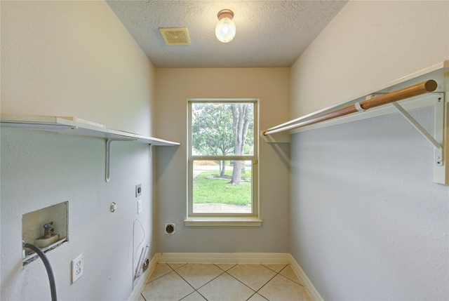 6613 Whitton Dr, Houston, TX 77085 - laundry room featuring electric dryer hookup, washer hookup, light tile patterned floors, a textured ceiling, and baseboards