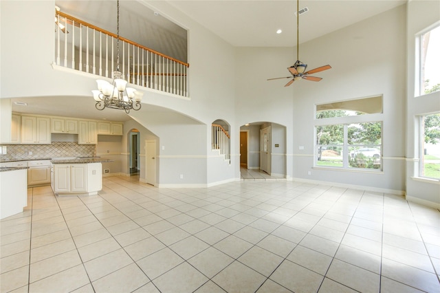 6613 Whitton Dr, Houston, TX 77085 - unfurnished living room with arched walkways, a towering ceiling, ceiling fan, light tile patterned floors, and a chandelier