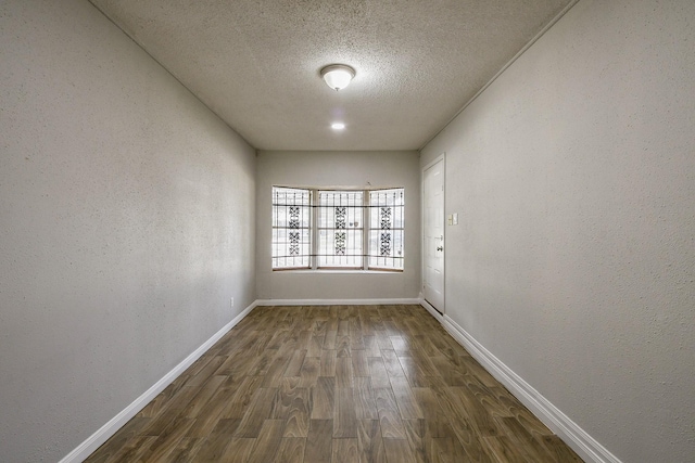 9923 Valley Sun Dr, Houston, TX 77078 - unfurnished room with dark wood-type flooring, baseboards, a textured ceiling, and a textured wall