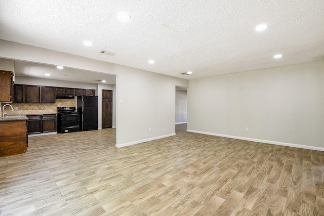 9923 Valley Sun Dr, Houston, TX 77078 - unfurnished living room with a sink, a textured ceiling, recessed lighting, light wood-type flooring, and baseboards