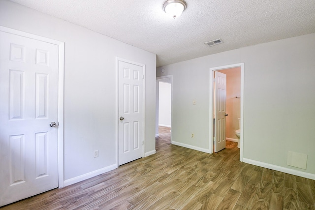9923 Valley Sun Dr, Houston, TX 77078 - unfurnished bedroom featuring light wood-type flooring, a textured ceiling, baseboards, and ensuite bath