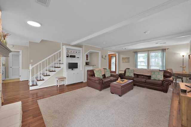 living room with stairs, dark wood-style flooring, and beam ceiling