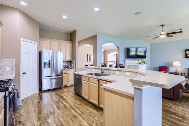 18115 Linden Forest Ln, Katy, TX 77449 - kitchen featuring appliances with stainless steel finishes, a sink, open floor plan, arched walkways, and light brown cabinetry
