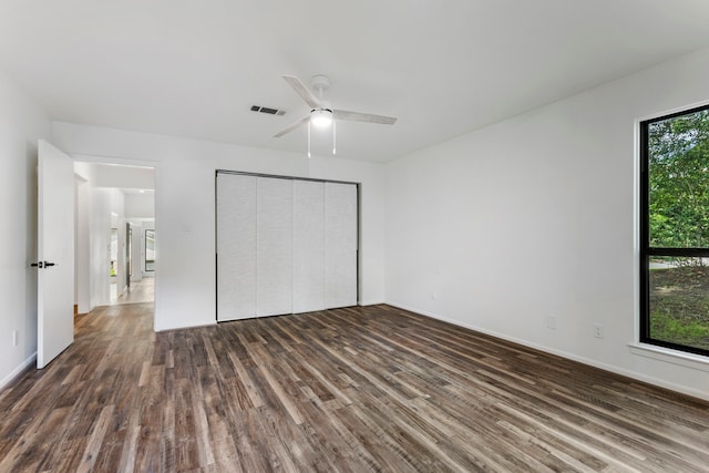 unfurnished bedroom featuring wood finished floors, a closet, a ceiling fan, and baseboards
