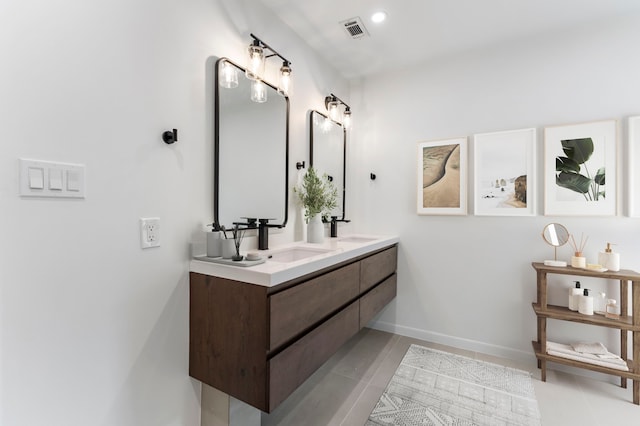 bathroom featuring double vanity, tile patterned flooring, and baseboards