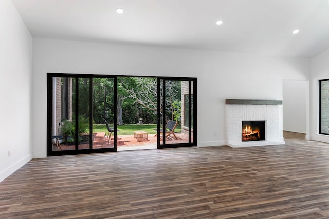 unfurnished living room featuring wood finished floors, a brick fireplace, recessed lighting, and baseboards