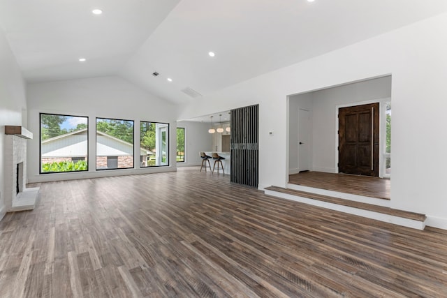 unfurnished living room with high vaulted ceiling, wood finished floors, a brick fireplace, recessed lighting, and baseboards