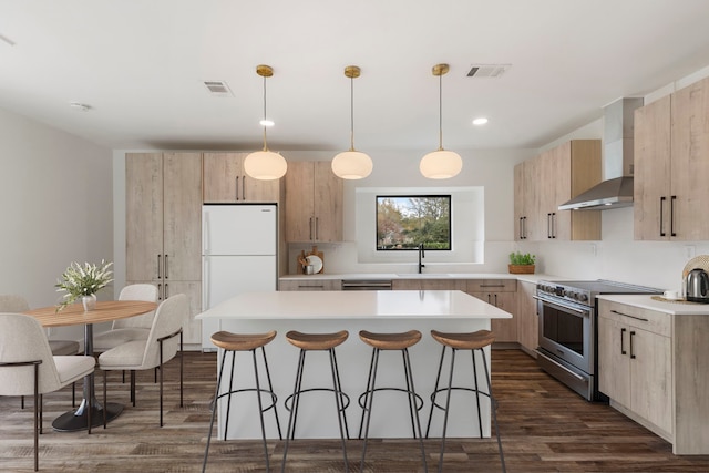 kitchen with high end range, light brown cabinets, a sink, wall chimney range hood, and recessed lighting