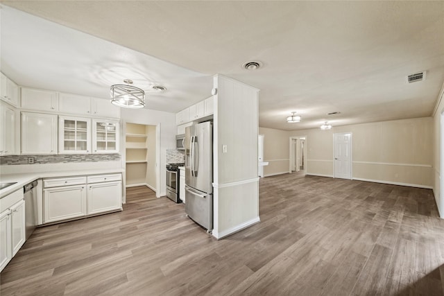 kitchen featuring stainless steel appliances, white cabinetry, a chandelier, light wood-style floors, and tasteful backsplash