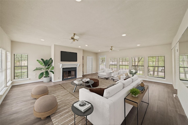 living room with wood finished floors, a fireplace, baseboards, ceiling fan, and recessed lighting