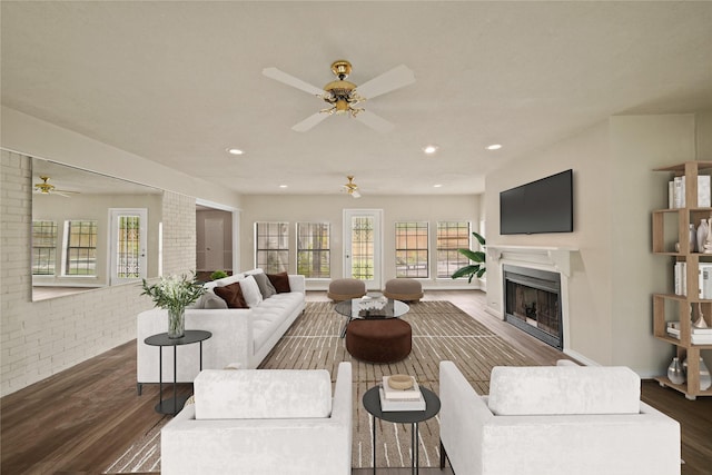 living area featuring a ceiling fan, a fireplace, dark wood-style flooring, brick wall, and recessed lighting