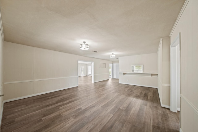 unfurnished living room with dark wood finished floors, baseboards, and a textured ceiling