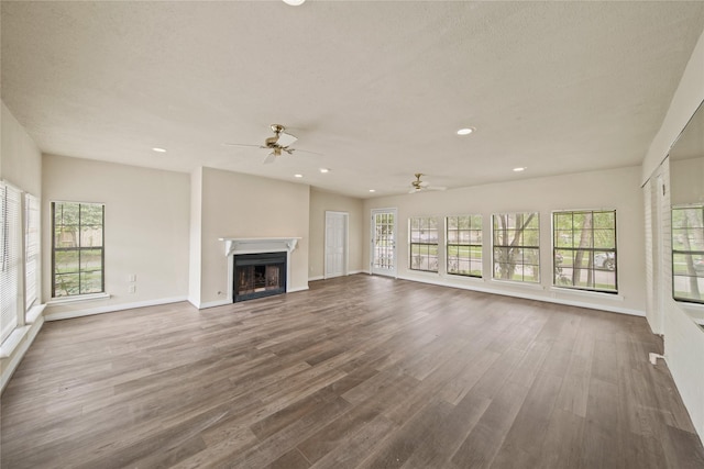 unfurnished living room featuring plenty of natural light, ceiling fan, a fireplace, and recessed lighting