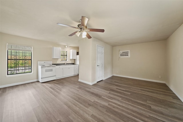 unfurnished living room with a sink, a ceiling fan, wood finished floors, and baseboards