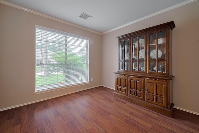unfurnished room with wood finished floors, crown molding, and baseboards