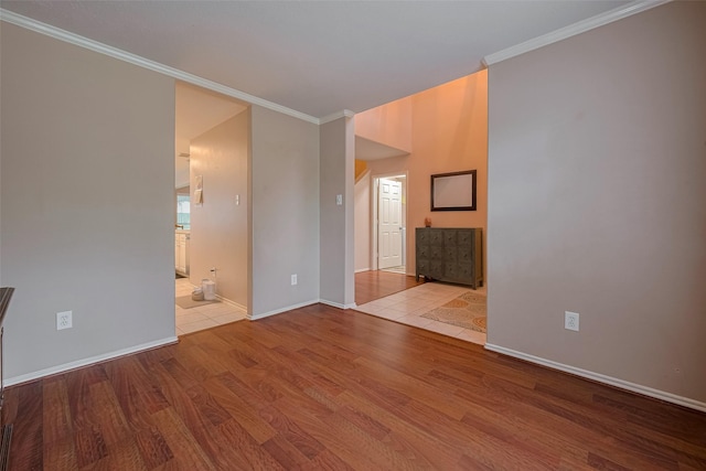 unfurnished room featuring wood finished floors, baseboards, and crown molding