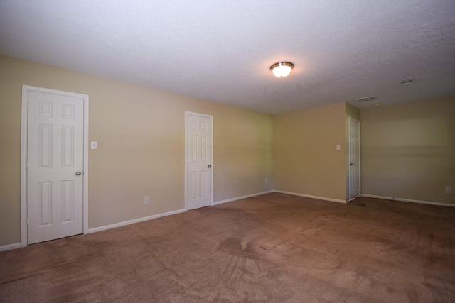 carpeted spare room featuring baseboards and a textured ceiling