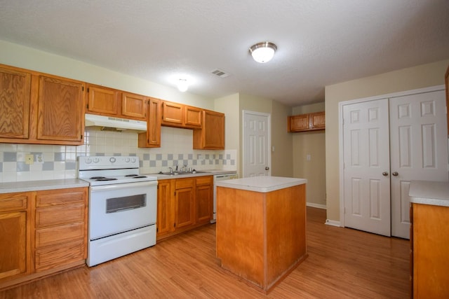 kitchen featuring white range with electric cooktop, under cabinet range hood, a sink, dishwasher, and light wood finished floors