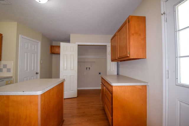 kitchen featuring light wood-style floors, brown cabinetry, light countertops, healthy amount of natural light, and a textured ceiling