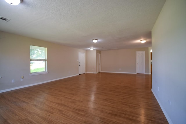empty room featuring wood finished floors, a textured ceiling, and baseboards