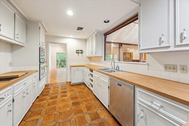 kitchen featuring appliances with stainless steel finishes, a sink, butcher block countertops, plenty of natural light, and recessed lighting