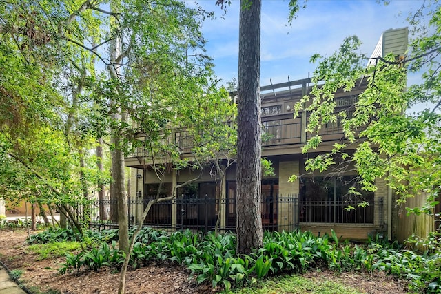 back of house featuring a balcony, fence, and a chimney