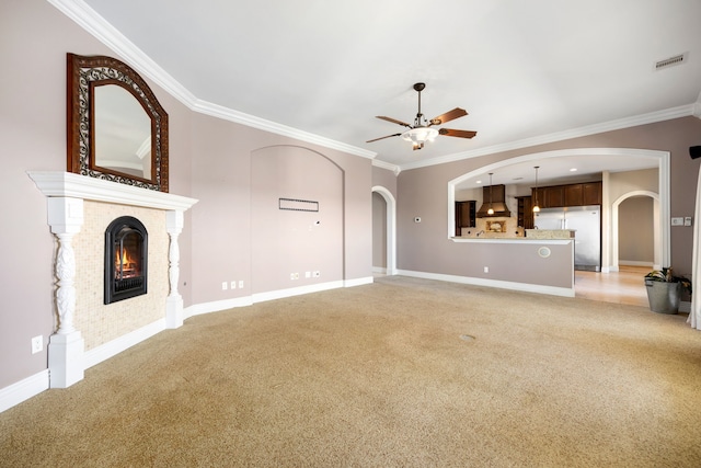 4343 Schlipf Rd, Katy, TX 77493 - unfurnished living room featuring light carpet, arched walkways, ceiling fan, crown molding, and a fireplace