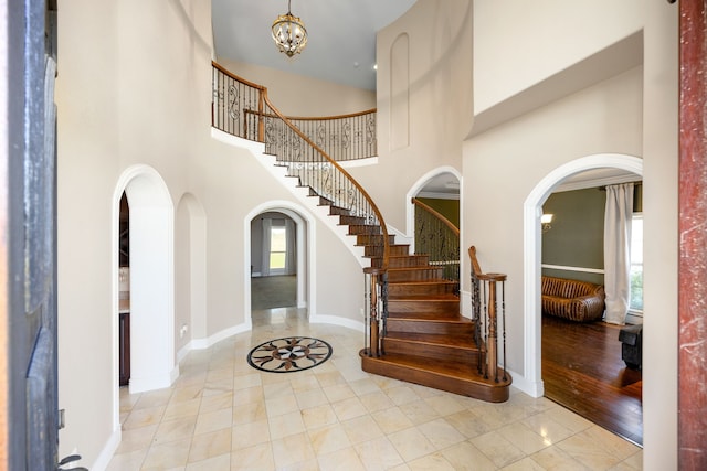 4343 Schlipf Rd, Katy, TX 77493 - entryway with arched walkways, a high ceiling, stairs, baseboards, and a chandelier