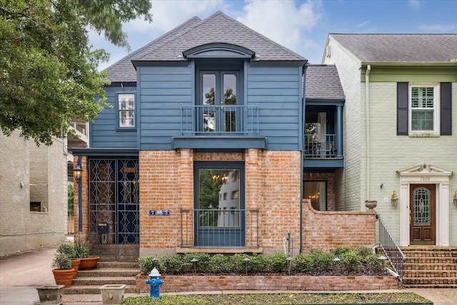 7603 Olympia Dr, Houston, TX 77063 - view of front facade featuring roof with shingles, brick siding, and a balcony