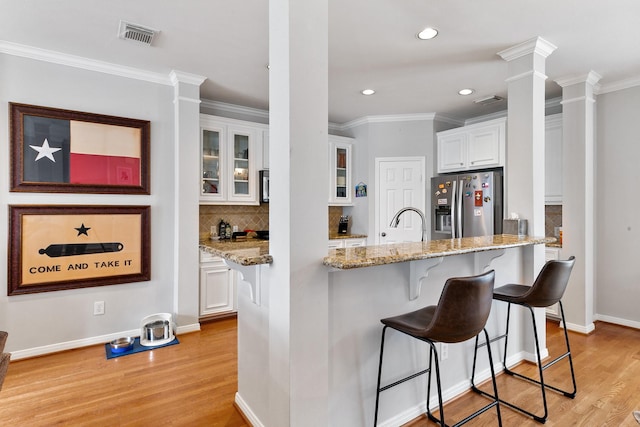 1708 Wilson St, Houston, TX 77019 - kitchen with stainless steel fridge, decorative columns, light wood-type flooring, white cabinetry, and recessed lighting