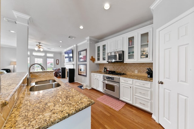 1708 Wilson St, Houston, TX 77019 - kitchen featuring stainless steel appliances, a sink, ornamental molding, light wood-style flooring, and open floor plan