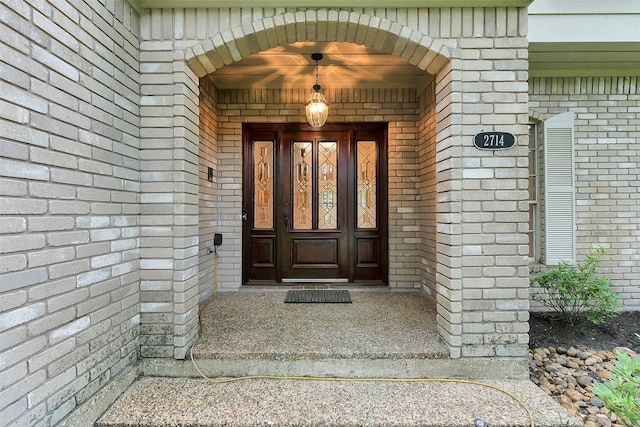 view of exterior entry featuring brick siding